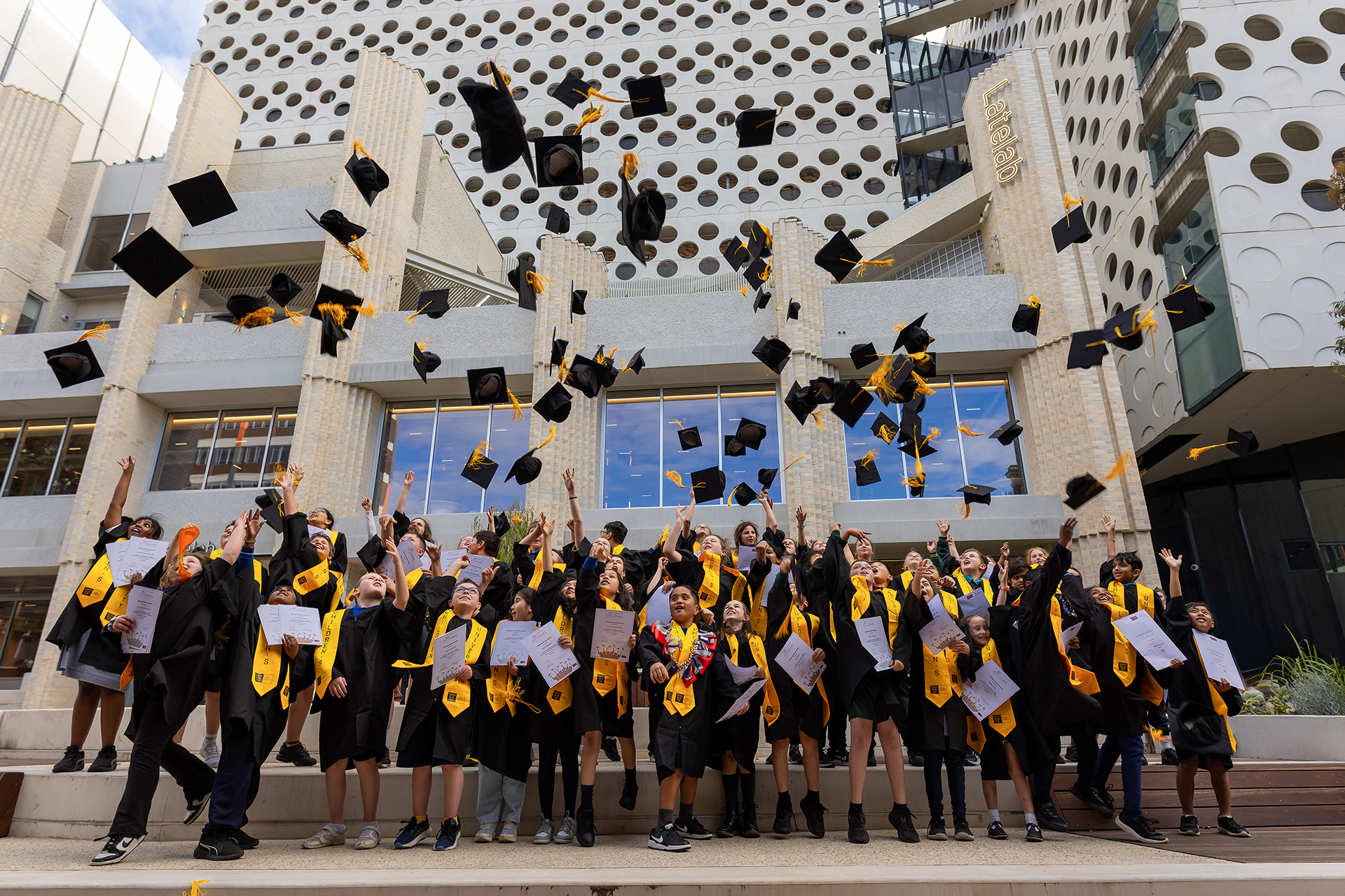 Swinburne Children’s University graduates celebrating together with their caps in the air