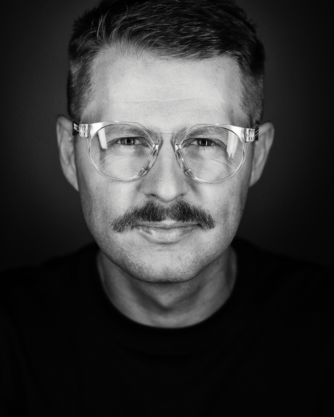 Creative black-and-white professional headshot of a man with clear glasses