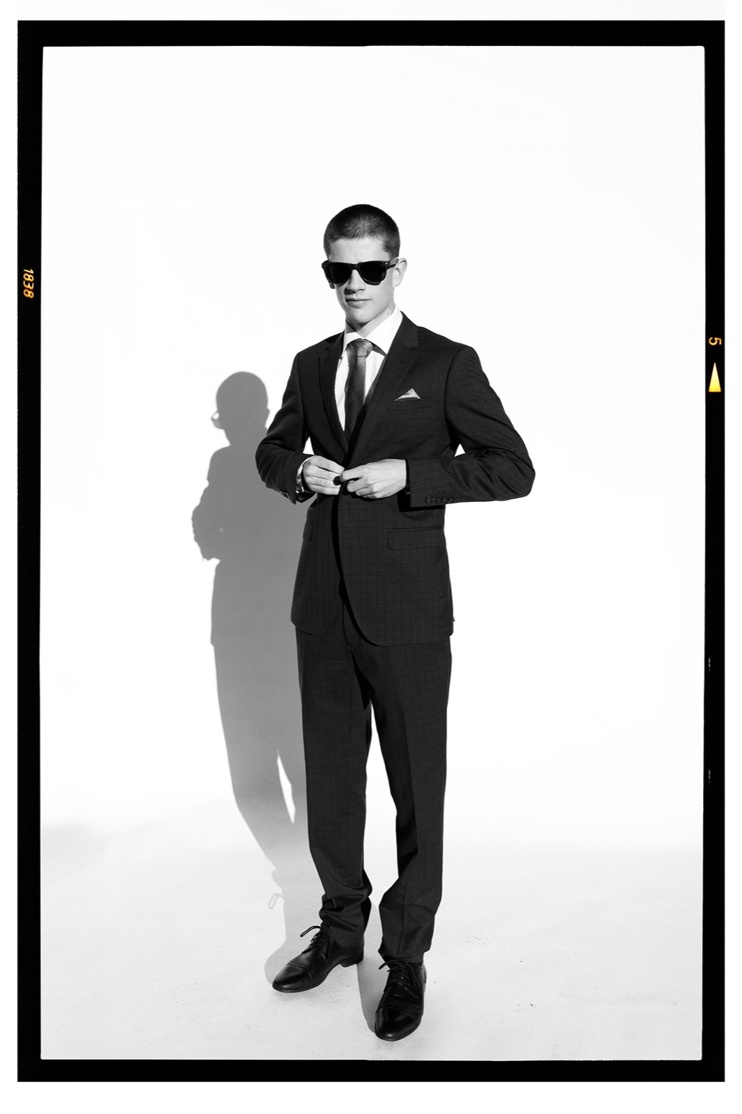 Full-length editorial portrait of a man in a suit and sunglasses