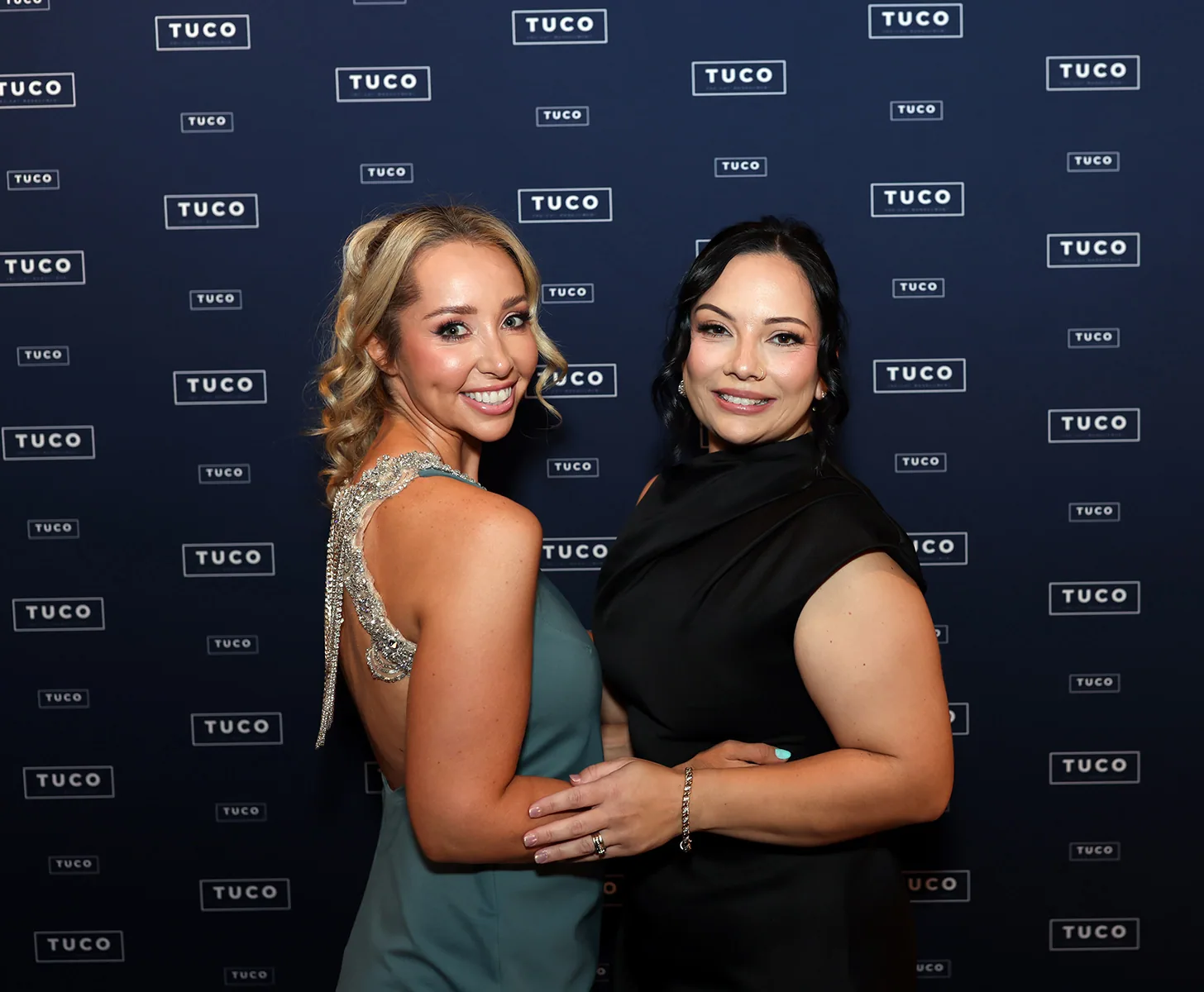 Two guests photographed against a Tuco branded media wall at a Melbourne gala